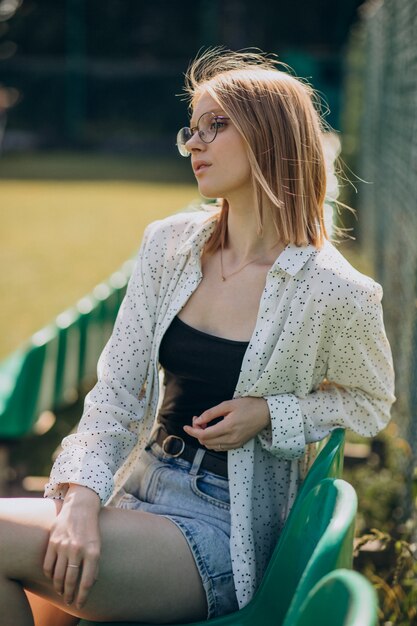 Ragazza pon pon della donna che si siede al campo di calcio