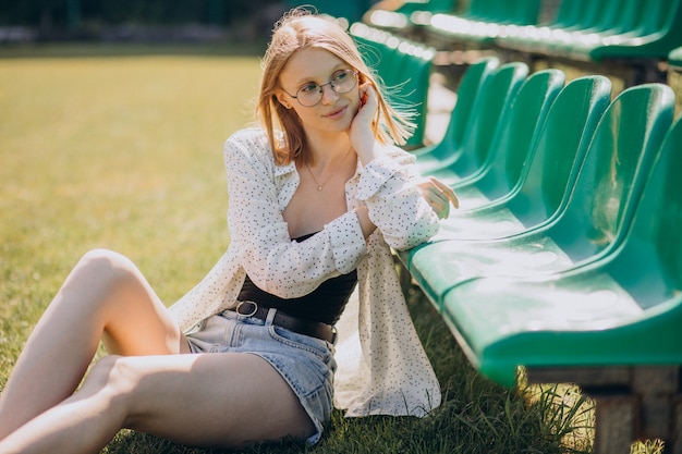 Ragazza pon pon della donna che si siede al campo di calcio