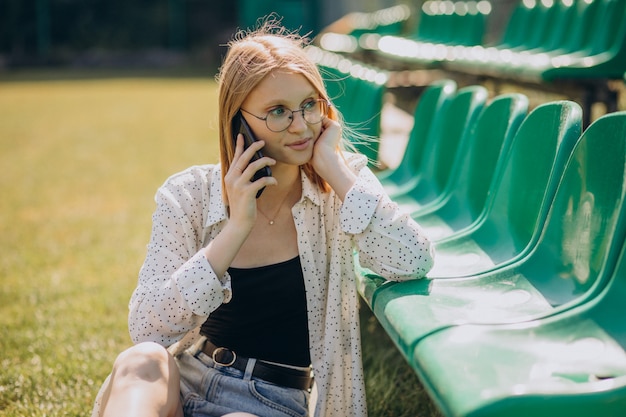 Ragazza pon pon della donna che si siede al campo di calcio