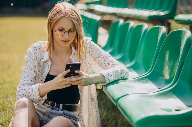 Ragazza pon pon della donna che si siede al campo di calcio