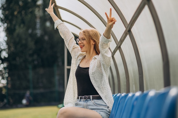 Ragazza pon pon della donna che si siede al campo di calcio