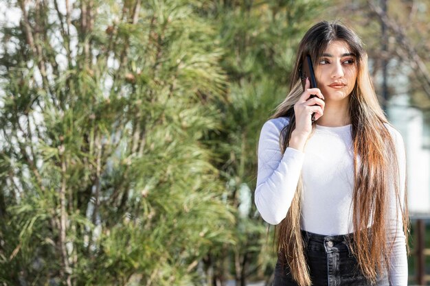 Ragazza premurosa che parla al telefono al parco Foto di alta qualità