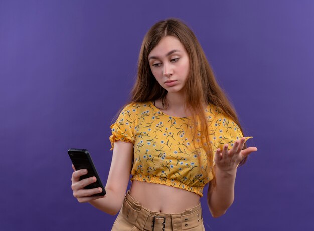 Ragazza premurosa che tiene il telefono cellulare e guardarlo sulla parete viola isolata