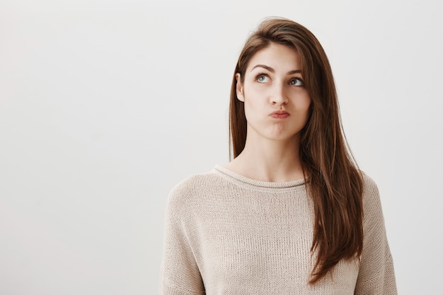 Ragazza premurosa indecisa che prende una decisione, guardando esitante nell'angolo in alto a sinistra