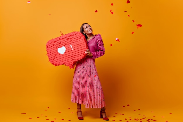 Ragazza romantica sognante di ottimo umore durante il servizio fotografico con un grande simile nelle sue mani. modello in camicetta alla moda con balza