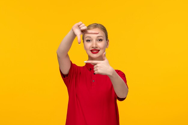 Ragazza rossa di happu di giorno della camicia in una camicia rossa su un fondo giallo che mostra le mani quadrate