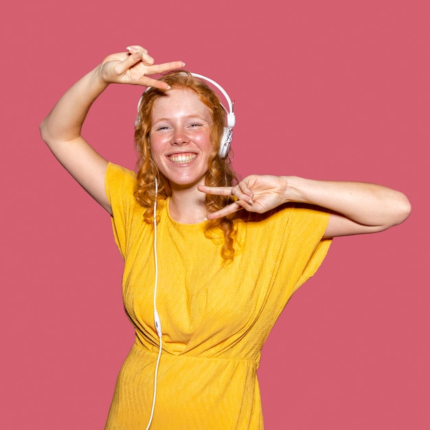 Ragazza rossa felice che ascolta la musica tramite le cuffie