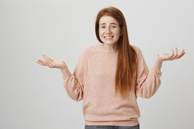 Ragazza rossa goffa con i capelli rossi che scrolla le spalle, scusandosi per essere inconsapevole