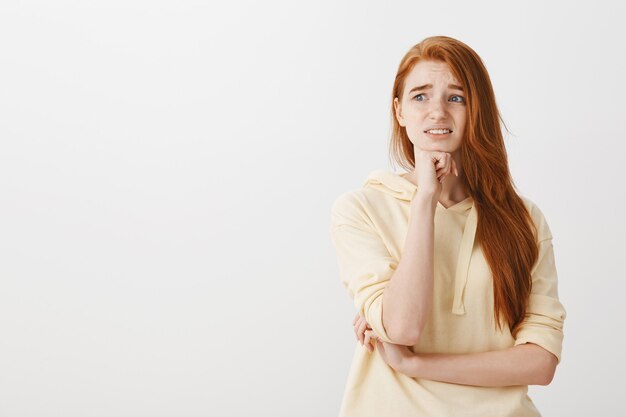 Ragazza rossa preoccupata in preda al panico, guardando a sinistra sopraffatta