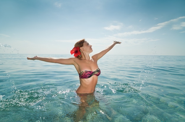 Ragazza rossa sexy che indossa bikini che gode dell&#39;acqua