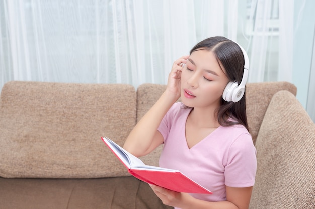 Ragazza sdraiata sul divano ascoltando musica e leggendo libri.