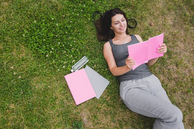 Ragazza sdraiata sul taccuino di lettura dell&#39;erba