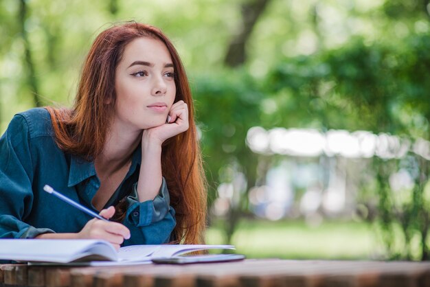 Ragazza sdraiata sul tavolo nella scrittura del parco