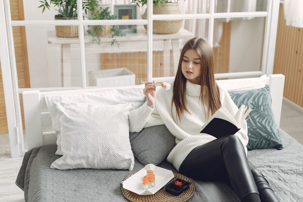 Ragazza seduta a casa su un divano con un sushi