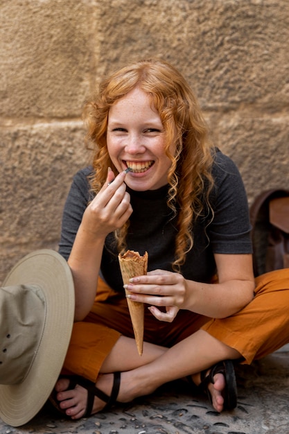 Ragazza seduta a terra e mangia il cono gelato