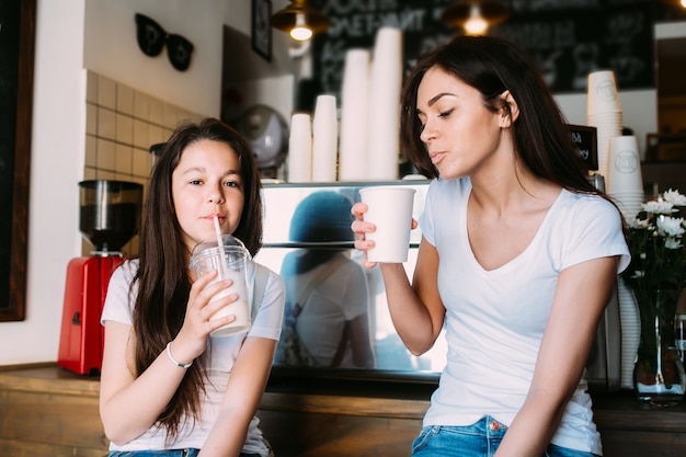 Ragazza seduta in caffè che tengono le coppe bere