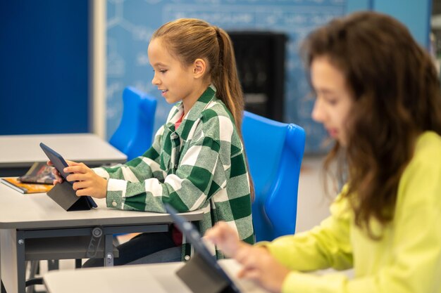 Ragazza seduta lateralmente alla telecamera guardando tablet