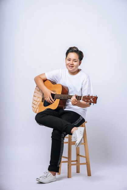 Ragazza seduta su una sedia e suonare la chitarra.