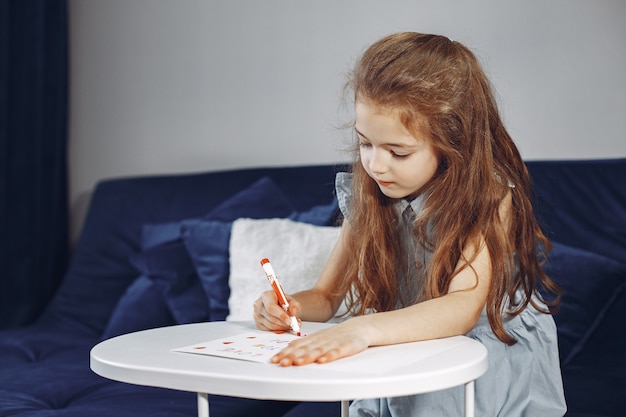 Ragazza seduta sul divano. Divano blu. Il bambino disegna.