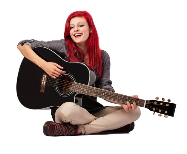 Ragazza seduta sul pavimento e giocare la sua chitarra