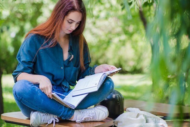 Ragazza seduta sul tavolo in lettura parco