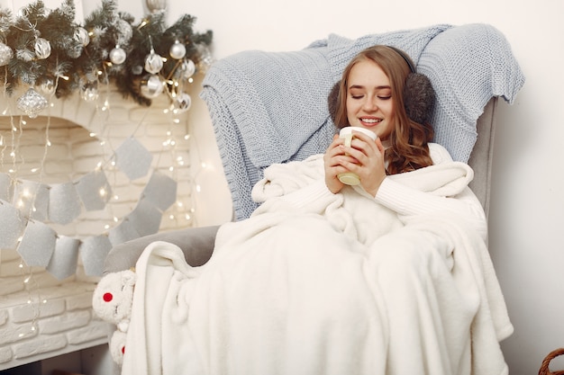 Ragazza seduta sulla sedia .Donna con la tazza. Signora che prepara per il Natale.