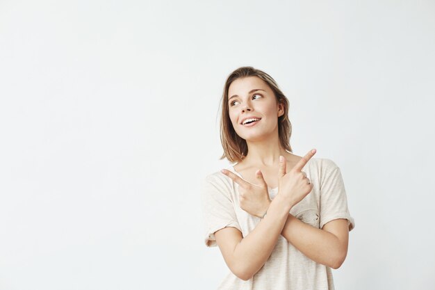 Ragazza sincera felice che indica le dita su che sorridono.