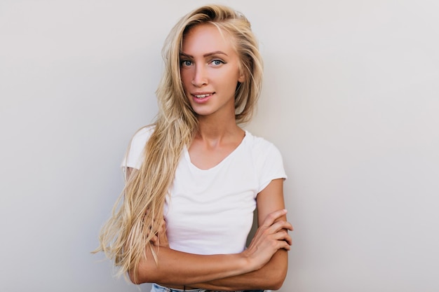 Ragazza snella romantica che posa in studio con un sorriso dolce Signora caucasica allegra con capelli lunghi che guarda alla macchina fotografica