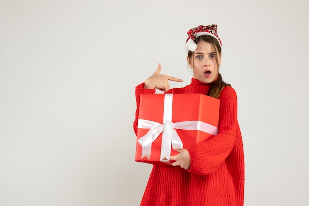 ragazza sorpresa con il cappello della Santa che tiene il dito presente che punta se stessa in piedi sul bianco