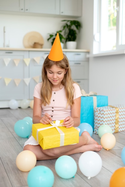 Ragazza sorridente a tutto campo che tiene un regalo carino