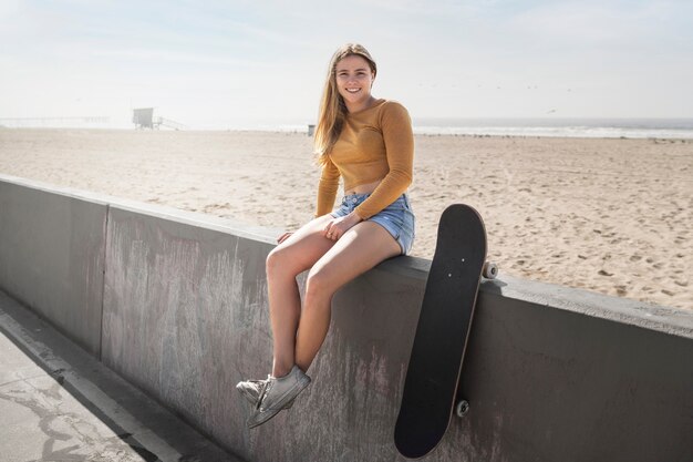 Ragazza sorridente a tutto campo con lo skateboard