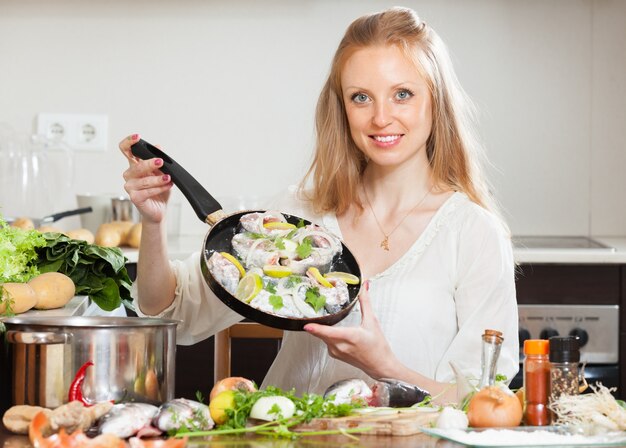 Ragazza sorridente che cucina pesce con il limone