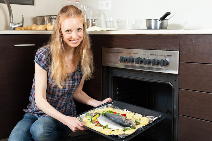 Foto gratuito ragazza sorridente che cucina pesce crudo in forno