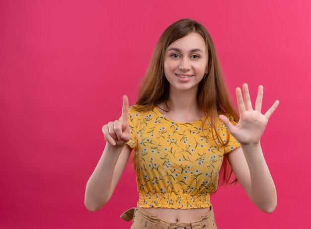 Ragazza sorridente che mostra uno e cinque sulla parete rosa isolata con lo spazio della copia