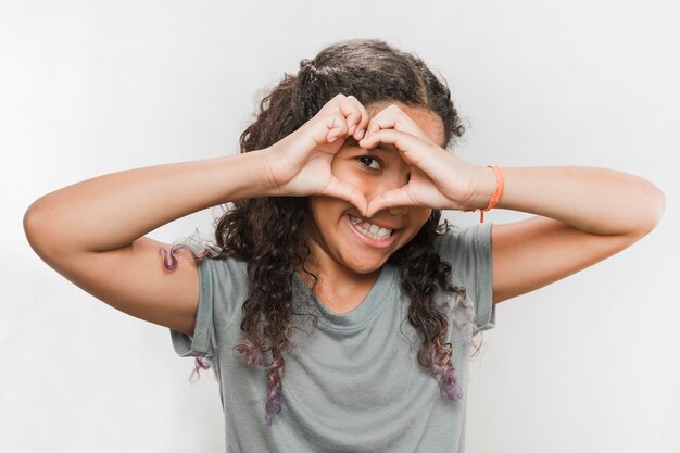 Ragazza sorridente che osserva attraverso la figura del cuore