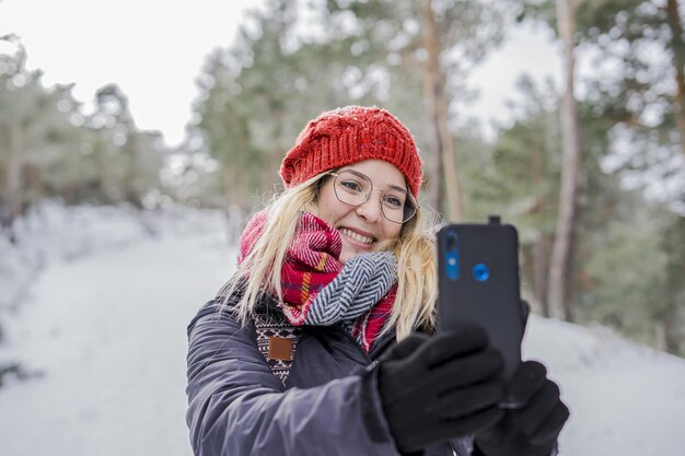 Ragazza sorridente che si gode l'inverno e si fa un selfie mentre nevica