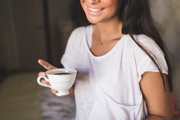 Ragazza sorridente che tiene tazza di caffè