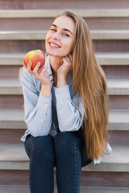 Ragazza sorridente che tiene una mela deliziosa