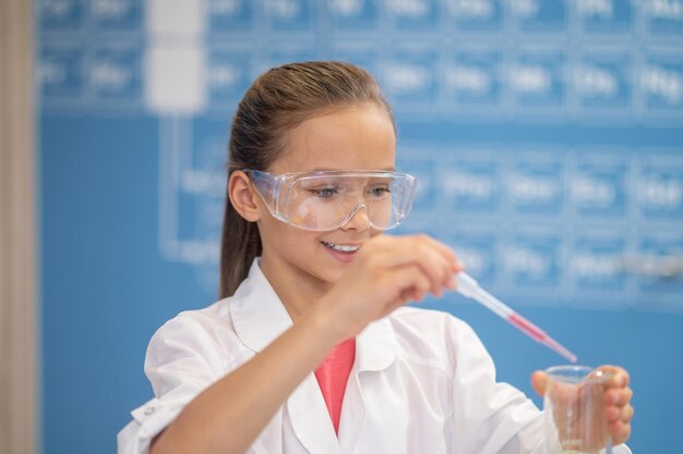 Ragazza sorridente con pipetta e provetta