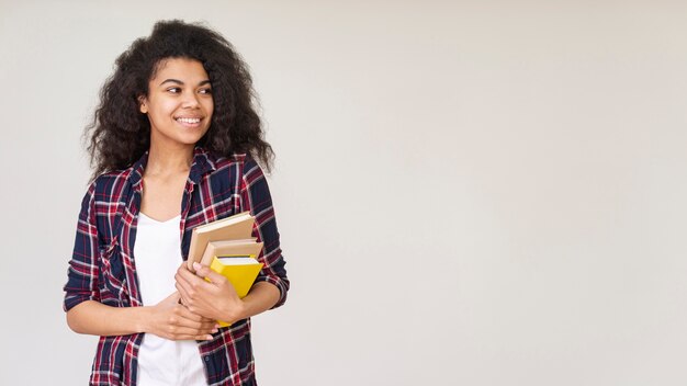 Ragazza sorridente con una pila di libri