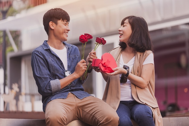 Ragazza sorridente con una scatola di cioccolatini e rose