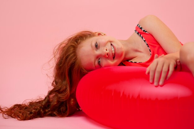 Ragazza sorridente del colpo medio che pone sull'ancora di salvezza rossa