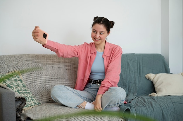 Ragazza sorridente del colpo pieno che prende selfie