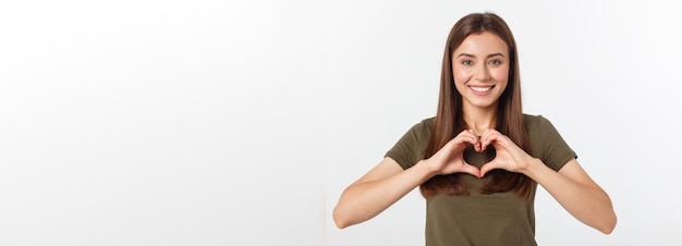 Ragazza sorridente dell'adolescente che fa forma del cuore con le sue mani isolate su bianco