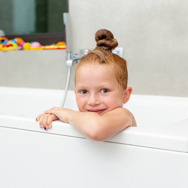 Ragazza sorridente di smiley nella vasca da bagno