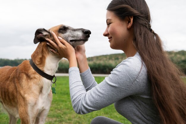 Ragazza sorridente di vista laterale che accarezza il cane