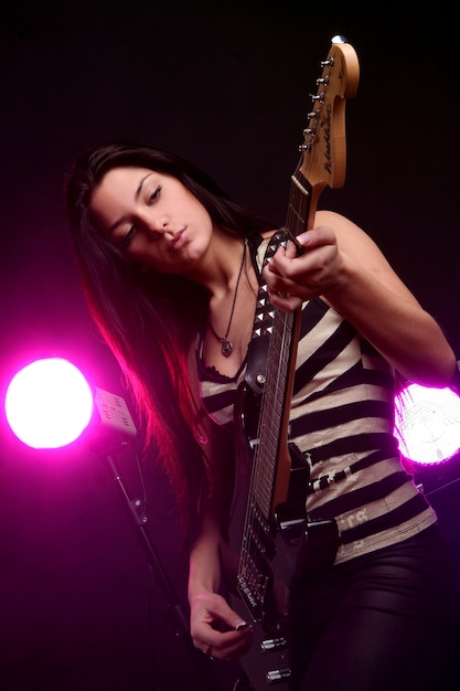 Ragazza sorridente felice che gioca chitarra