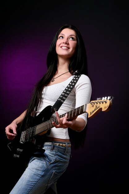 Ragazza sorridente felice che gioca chitarra