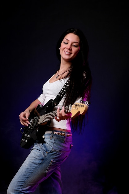 Ragazza sorridente felice che gioca chitarra