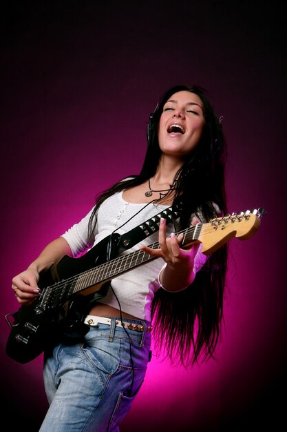 Ragazza sorridente felice che gioca chitarra